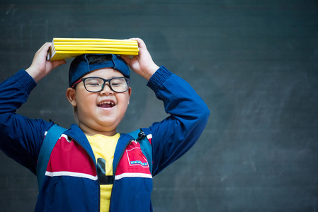 快乐微笑的亚洲男孩在眼镜是第一次去学校。孩子带着书包和书。教室里的孩子们, 房间里有黑板的背景。返回学校概念