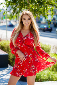 在红色礼服, 夏天街道户外的年轻美丽的金发女郎的肖像特写