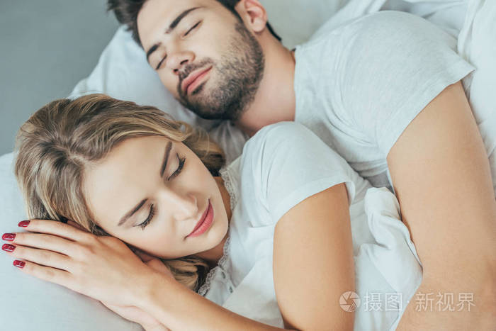 特写镜头的美丽的年轻夫妇睡在一起在床上在家