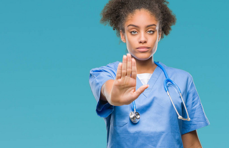年轻的美国黑人医生在孤立的背景下做停止唱歌与手掌的手。脸上带有否定和严肃手势的警告表达式