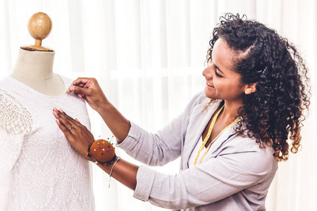 微笑的非洲裔美国黑人妇女时装设计师站在工作和使用的磁带表穿着衣服上的模特在车间工作室