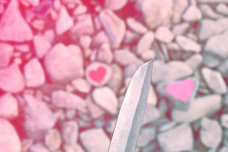 切割刀潜水粉红色的心涂在一块石头上的口红。爱的终结和两个人分手和离婚的象征