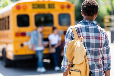 美国黑人学生后视图步行到同学靠校车