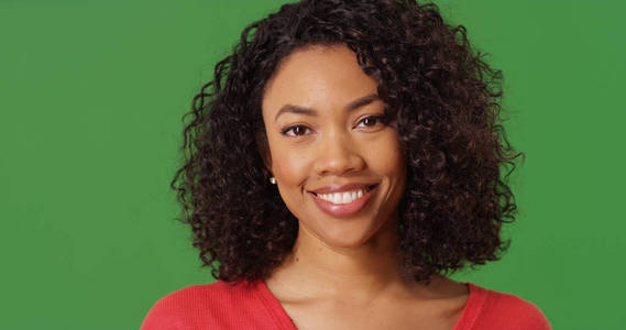 美丽的黑色千禧年女性的肖像微笑在照相机在绿色屏幕上