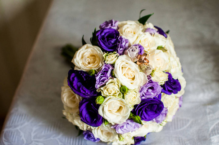 紫罗兰和白色的花朵花束与金色的戒指在桌子上