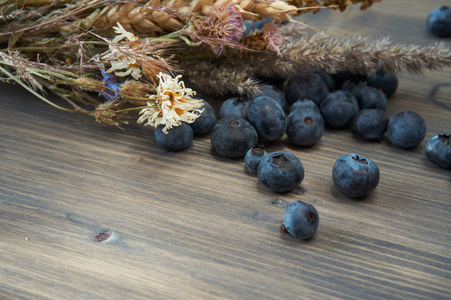 鲜蓝莓和干花花束在小角度选择性聚焦和复制空间的木制乡村板上