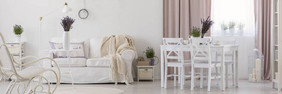 全景白色公寓内饰与椅子在餐桌旁的沙发与毯子。真实照片