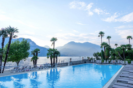 酒店泳池日落。科莫湖, 棕榈树和山脉背景。意大利贝拉吉奥