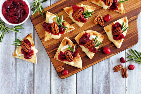 假日平底锅开胃菜配红莓山核桃和奶酪。木制盘子上的顶视图桌景