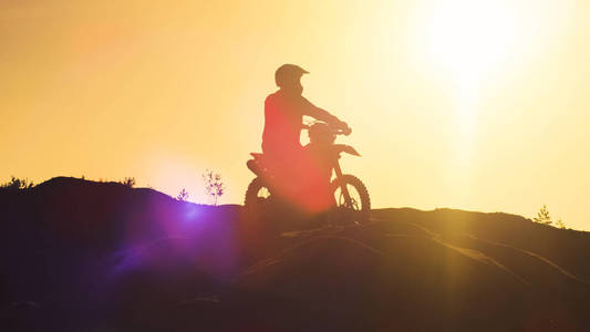 专业摩托车越野赛车手 Fmx 摩托车上站在沙丘和俯瞰极端越野地形他乘坐今天去