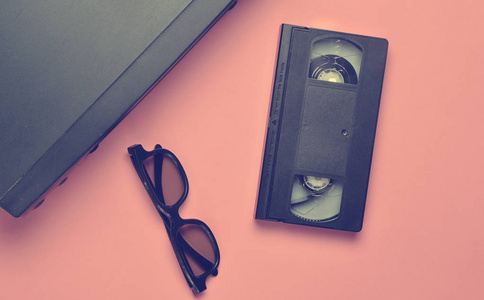 Vhs 播放器, 录像带, 3d 眼镜在粉红色的背景。过时的媒体技术。顶部视图