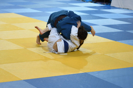 两个女孩柔道运动员在和服竞争 tatam