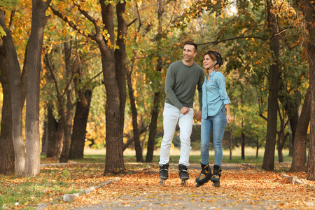 年轻夫妇在秋季公园轮滑