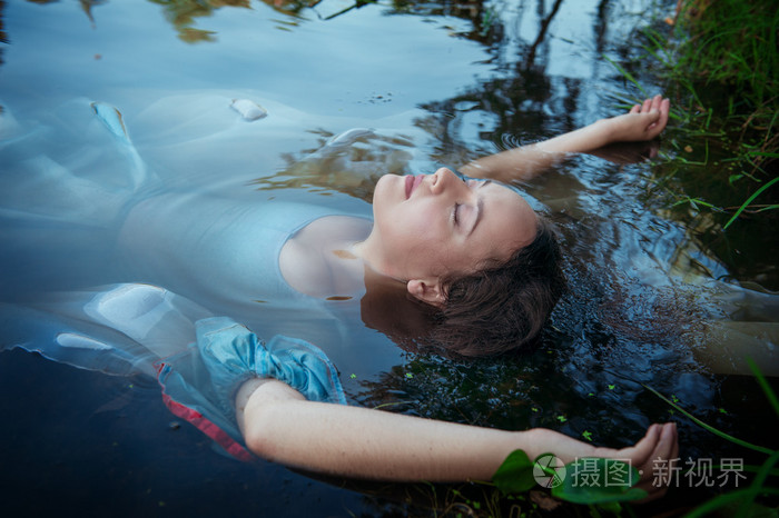 年轻美女穿着蓝色的衣服躺在河里淹死