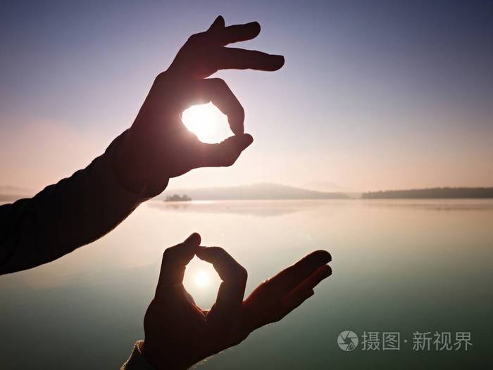 手在海水水平较低的太阳的强烈阳光下形成象征.可爱的
