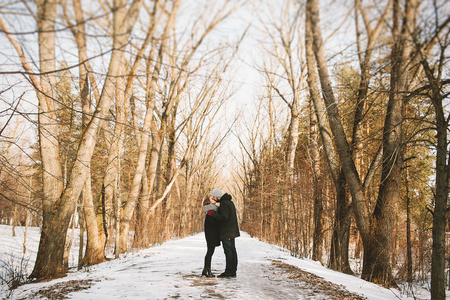 年轻的时髦夫妇在冬季森林中拥抱
