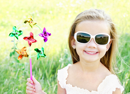 微笑的小女孩玩户外的风车玩具