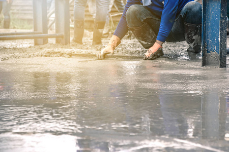 男子坐和使用木铲水泥后浇筑预拌混凝土的钢筋, 使道路混合移动混凝土搅拌机