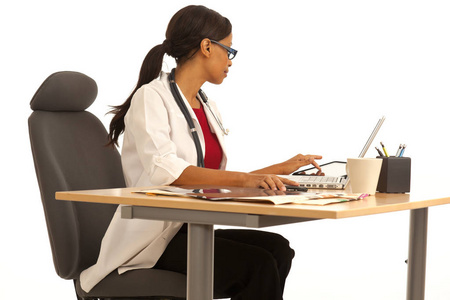 专业女医生使用笔记本电脑在她的办公桌前工作