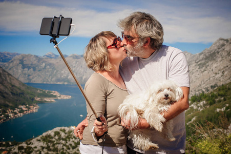 情侣情侣与美丽的狗拍摄自拍图片在海面上的背景。自拍照片棒。科托尔, 黑山