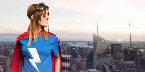 漂亮的超级英雄女孩看横向在摩天大楼城市