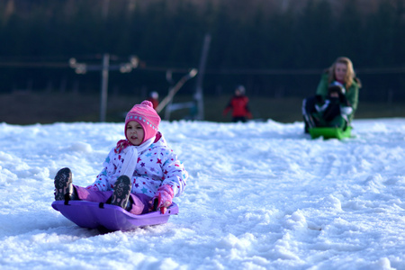 快乐的女孩滑雪橇，冬天好玩 雪 滑雪橇的家庭