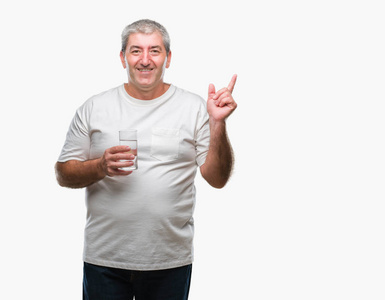 英俊的老人喝玻璃水在孤立的背景非常高兴地指着手和手指到一边
