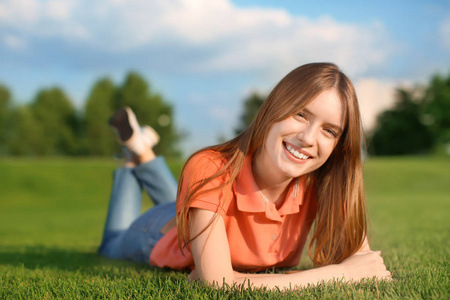 年轻女子躺在户外的绿草上