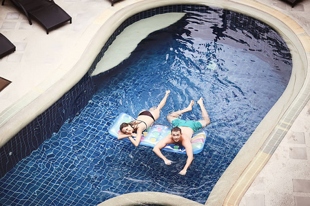 愉快的夫妇在夏季游泳池在酒店的乐趣