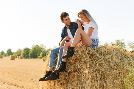 幸福的男人和女人的肖像坐在大干草在金色田野在晴朗的日子