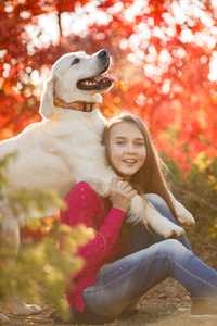 年轻的女孩坐在她的狗猎犬在秋天的场景中与地面上的肖像