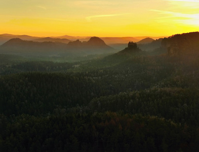 在美丽的山的捷克萨克森瑞士的日出。砂岩峰林雾从雾背景增加，是由于太阳光的橙色