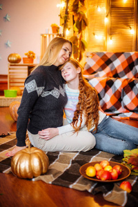 红头发的少女和她的妈妈在演播室秋天的风景与黄叶, 毯子, 苹果和南瓜