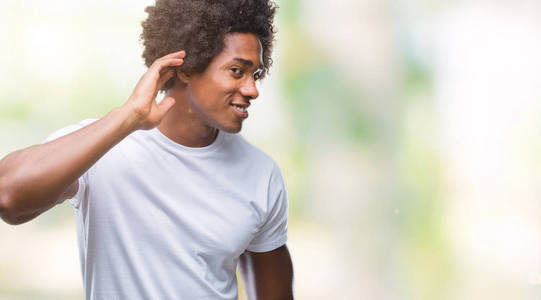 美国黑人在孤立的背景下微笑着, 用手在耳边听着谣言或流言蜚语。耳聋概念