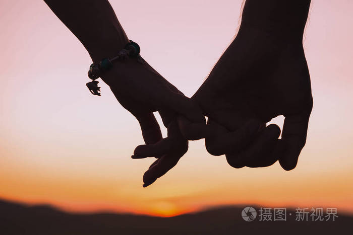 在落日的背景下, 女性和男性手牵手的剪影.关系,爱情