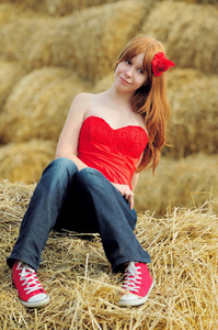 快乐微笑着的年轻女孩坐在干草上
