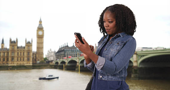 伦敦游客由大本钟沿泰晤士河在手机上的消息