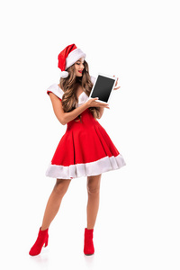 迷人的女孩在圣诞老人的服装呈现数字平板, 孤立的白色