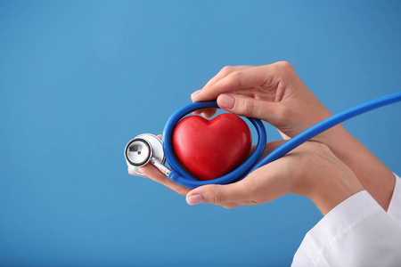 医用听诊器和红色心脏的心脏病专家在颜色背景