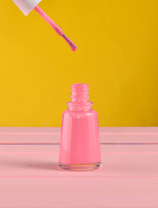 打开一瓶粉红色的指甲油在一个黄色的背景