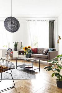 桌子上的向日葵在明亮的客厅内部, 扶手椅和靠近窗户的长椅。真实照片