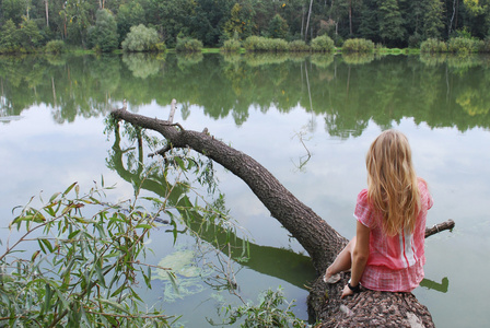 nia sentada en la orilla del lago en el rbol