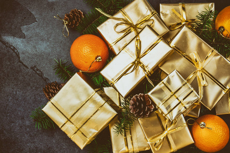 圣诞背景。金色礼品盒和圣诞装饰桔子, 圣诞树树枝和锥体在石板背景。平躺, 顶部视图