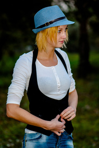 美丽的金发女孩构成中的森林里的帽子和时尚的衣服