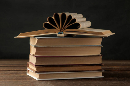 在褐色的木桌上和黑色背景上的一堆书。旧书。教育。学校。研究