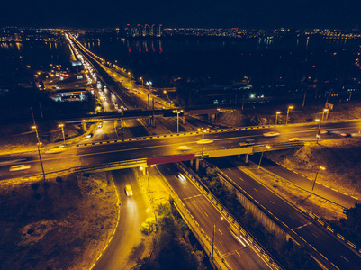 鸟瞰与桥梁和高速公路的路连接, 现代城市与夜照明和汽车交通