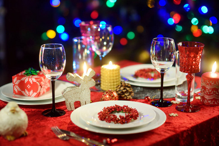 美丽的餐桌设置为圣诞晚会或新年庆祝在家里。舒适的房间里有壁炉和圣诞树的背景。圣诞节时间与家人和朋友