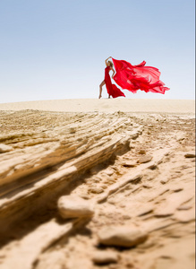 在沙漠中的美丽和苗条的女人，红色衣服