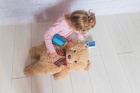 女孩, 一个孩子扮演医生, 测量熊玩具的压力