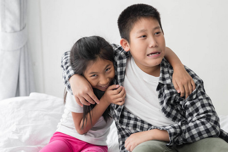 快乐亚洲青春期男孩拥抱他的妹妹在家